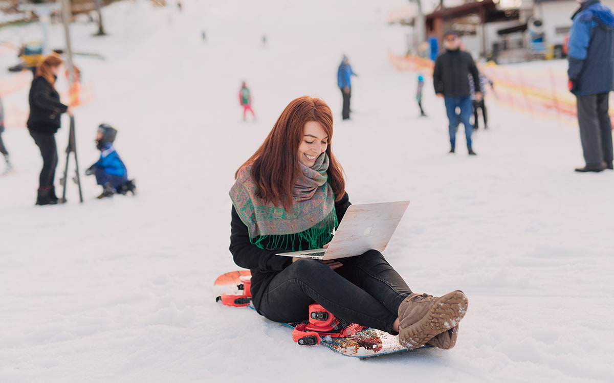 Girl working on her computer on a snowboard