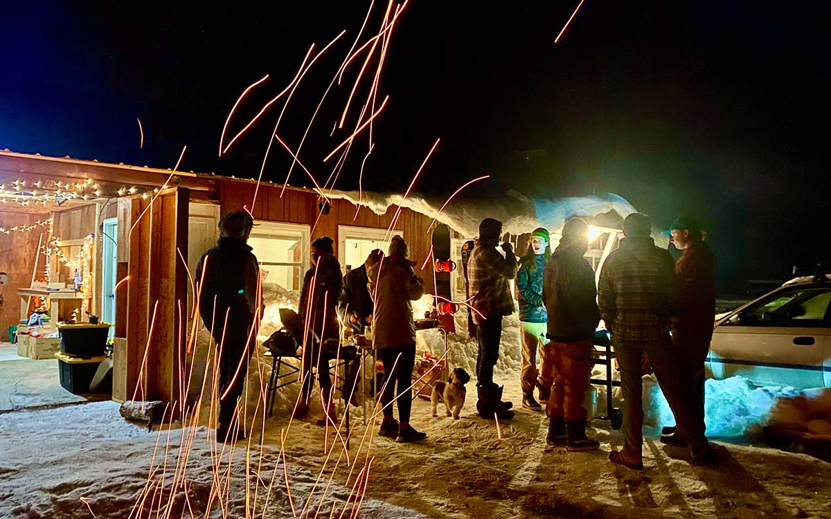 Snowboarders and Skiers for Christ in Whitefish waxing their skis and snowboards next to a fire.